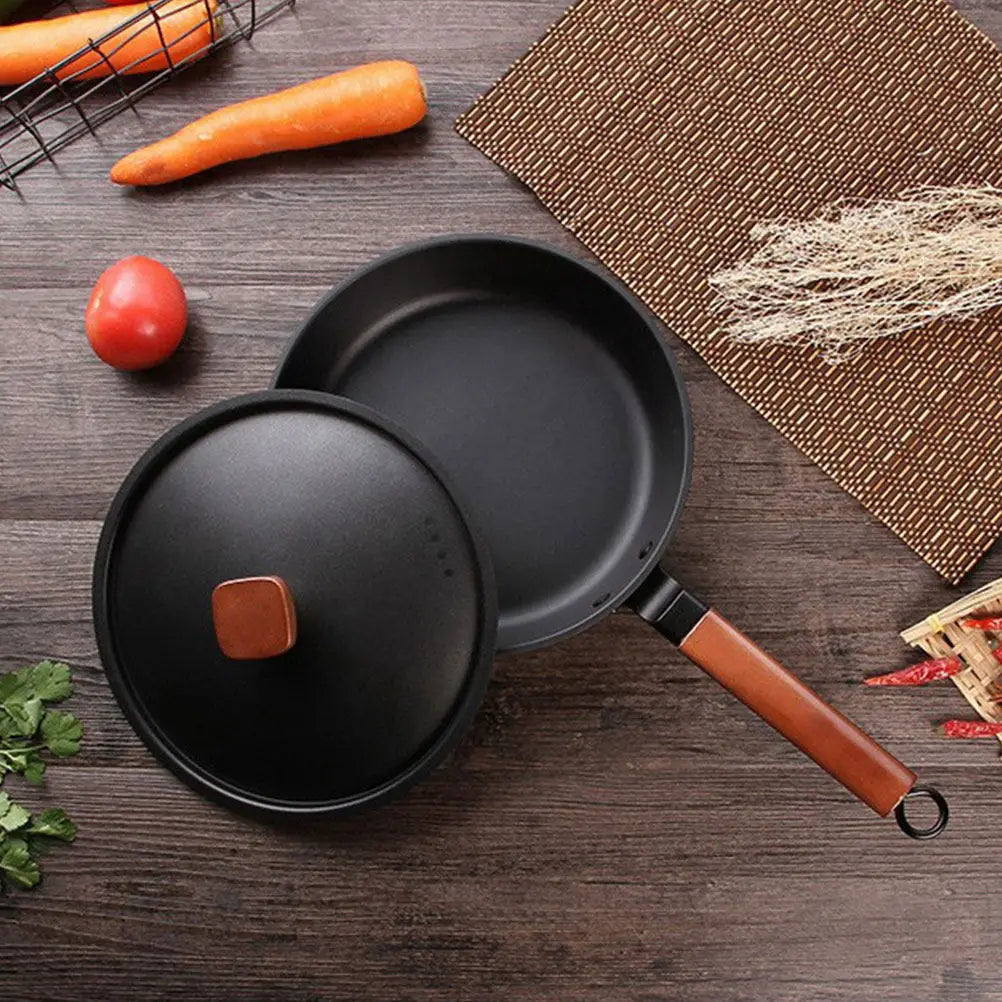 Wok KUROKO en acier carbone noir avec manche en bois et couvercle posé à côté sur une table