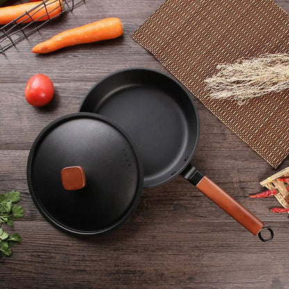 Wok KUROKO en acier carbone noir avec manche en bois et couvercle posé à côté sur une table