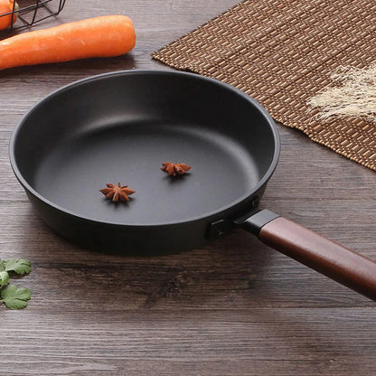 Gros plan de l’intérieur du wok KUROKO noir avec deux étoiles de badiane et son manche en bois.