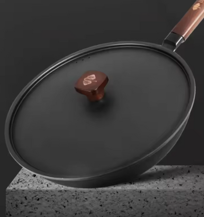 Wok KUROKO noir avec couvercle, bouton carré et manche en bois, posé sur un socle gris